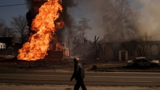 A man walks past flames and smoke rising from a fire following a Russian attack in Kharkiv, Ukraine, on Friday.(AP)
