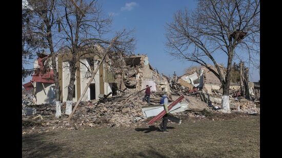 Locals clean up debris from the cultural centre destroyed in shelling earlier this month, as Russia's invasion of Ukraine continues, in the village of Byshiv outside Kyiv, Ukraine, March 24, 2022 (REUTERS)