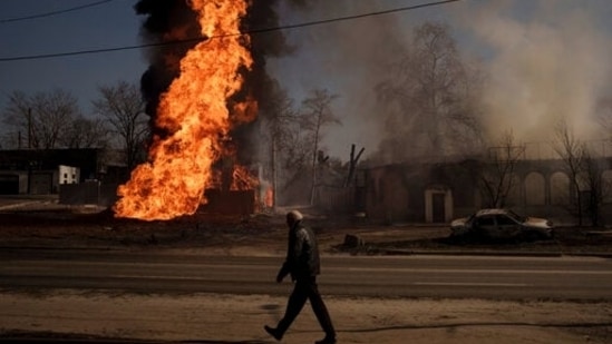 A man walks past flames and smoke rising from a fire following a Russian attack in Kharkiv, Ukraine, on Friday.