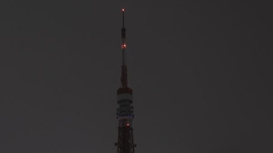 The landmark Tokyo Tower is seen with its lights off during Earth Hour in Tokyo, Japan, on March 26, 2022. (Photo by Charly TRIBALLEAU/AFP)