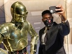 A person takes a selfie with a life-size figure of C-3PO at "The Fans Strike Back: The Largest Star Wars Fan Exhibition" in Manhattan, New York City.