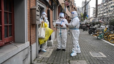 TOPSHOT - Health workers wearing protective gear as a measure against the Covid-19 coronavirus work along a street in Jing'an district in Shanghai on March 26, 2022. (Photo by Hector RETAMAL / AFP) (AFP)