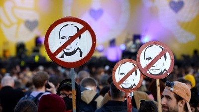People hold signs depicting Russia's President Wladymir Putin as they attend the charity concert ‘Yes We Care' for Ukraine, amid Russia's invasion. (REUTERS)