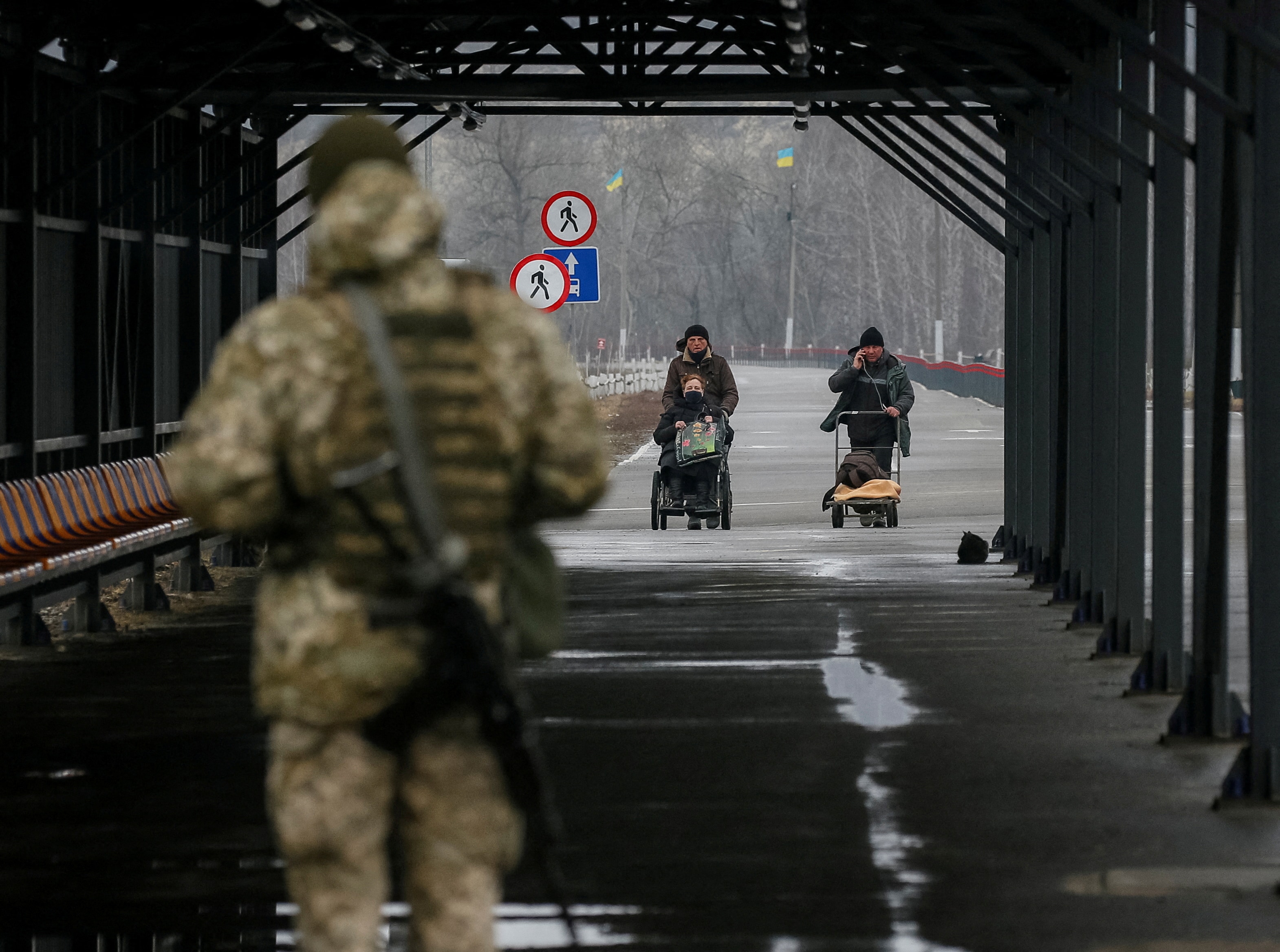 People cross the contact line between pro-Moscow rebels and Ukrainian troops as Ukrainian border guard guards in the settlement of Stanytsia Luhanska, Ukraine. (REUTERS/Gleb Garanich) (REUTERS)