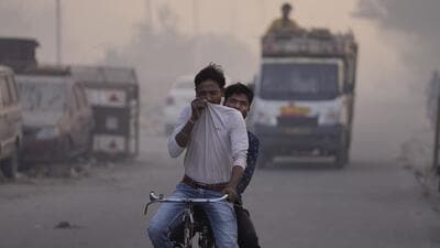 A cyclist covers face to save himself from the smoke as a massive fire engulfs the Ghazipur garbage dump in New Delhi, India, Monday. (AP)
