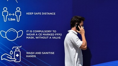 A person making a phone call with mask on, next to a banner with information on Covid-19 appropriate behaviour. (AFP) A person making a phone call with mask on, next to a banner with information on Covid-19 appropriate behaviour. (AFP)