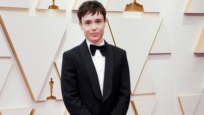 Elliot Page posed on the red carpet during the Oscars' arrivals at the 94th Academy Awards in a tailored black tuxedo. Their ensemble features a black coat, bow tie, white button-down, and pants. (REUTERS)