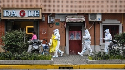 Health workers wearing protective gear as a measure against the Covid-19 coronavirus walk down a street in Jing'an district in Shanghai. (AFP) Health workers wearing protective gear as a measure against the Covid-19 coronavirus walk down a street in Jing'an district in Shanghai. (AFP)