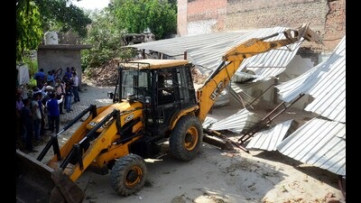 PDA team razing the boundary wall of mafiosi-turned-politician and former MP Atiq Ahmad’s residence at Chakia on Monday. (HT photo)