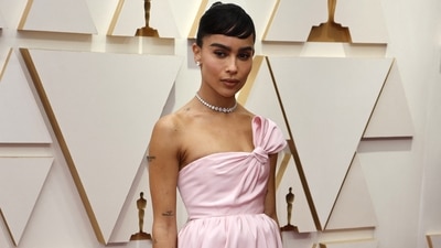 Zoë Kravitz took inspiration from Audrey Hepburn for her red carpet look at the 94th Academy Awards. The star showed up at Oscars in a baby pink Yves Saint Laurent dress with a knotted neckline to create a bow effect. She wore it with a diamond necklace and earrings, and a hairdo inspired by Audrey. 
