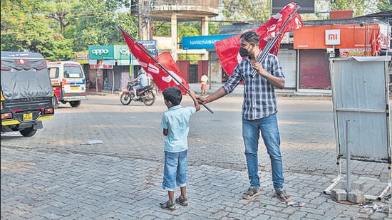 A boy assists a strike supporter erect flags at a town square on the first day of two day nationwide strike called by various labor unions in Kochi on Monday. (AP)