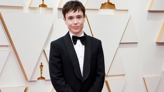 Elliot Page posed on the red carpet during the Oscars' arrivals at the 94th Academy Awards in a tailored black tuxedo. Their ensemble features a black coat, bow tie, white button-down, and pants.(REUTERS)