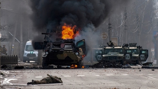 A file photo of a Russian armored personnel carrier burning amid damaged and abandoned light utility vehicles after fighting in Kharkiv, Ukraine