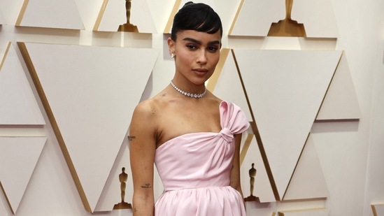 Zoë Kravitz took inspiration from Audrey Hepburn for her red carpet look at the 94th Academy Awards. The star showed up at Oscars in a baby pink Yves Saint Laurent dress with a knotted neckline to create a bow effect. She wore it with a diamond necklace and earrings, and a hairdo inspired by Audrey.