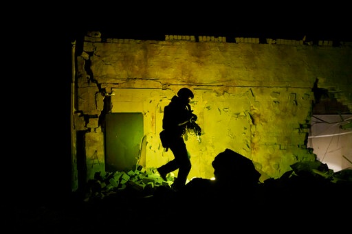 A Ukrainian special police officer walks next to a destroyed building as he patrols during night curfew in Kharkiv on March 27, 2022. (AP) A Ukrainian special police officer walks next to a destroyed building as he patrols during night curfew in Kharkiv on March 27, 2022. (AP)