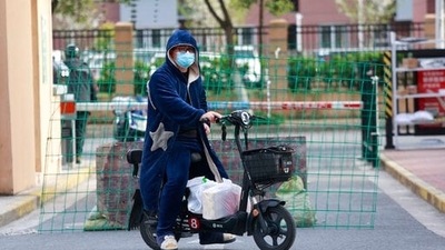 A man rides past a roadblock with his deliveries at a residential community under lock down in Shanghai, China, (AP) A man rides past a roadblock with his deliveries at a residential community under lock down in Shanghai, China, (AP)