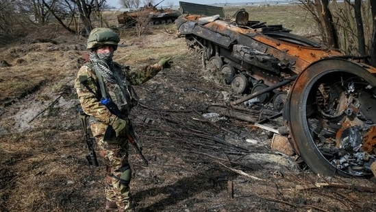 A Ukrainian serviceman stands near the wreck of a Russian armoured personnel carrier in the Kyiv region.(REUTERS)