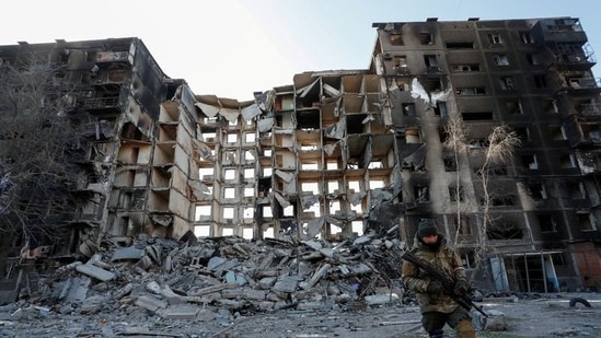 A service member of pro-Russian troops walks near an apartment building destroyed in the course of Ukraine-Russia conflict in the besieged southern port city of Mariupol, Ukraine.