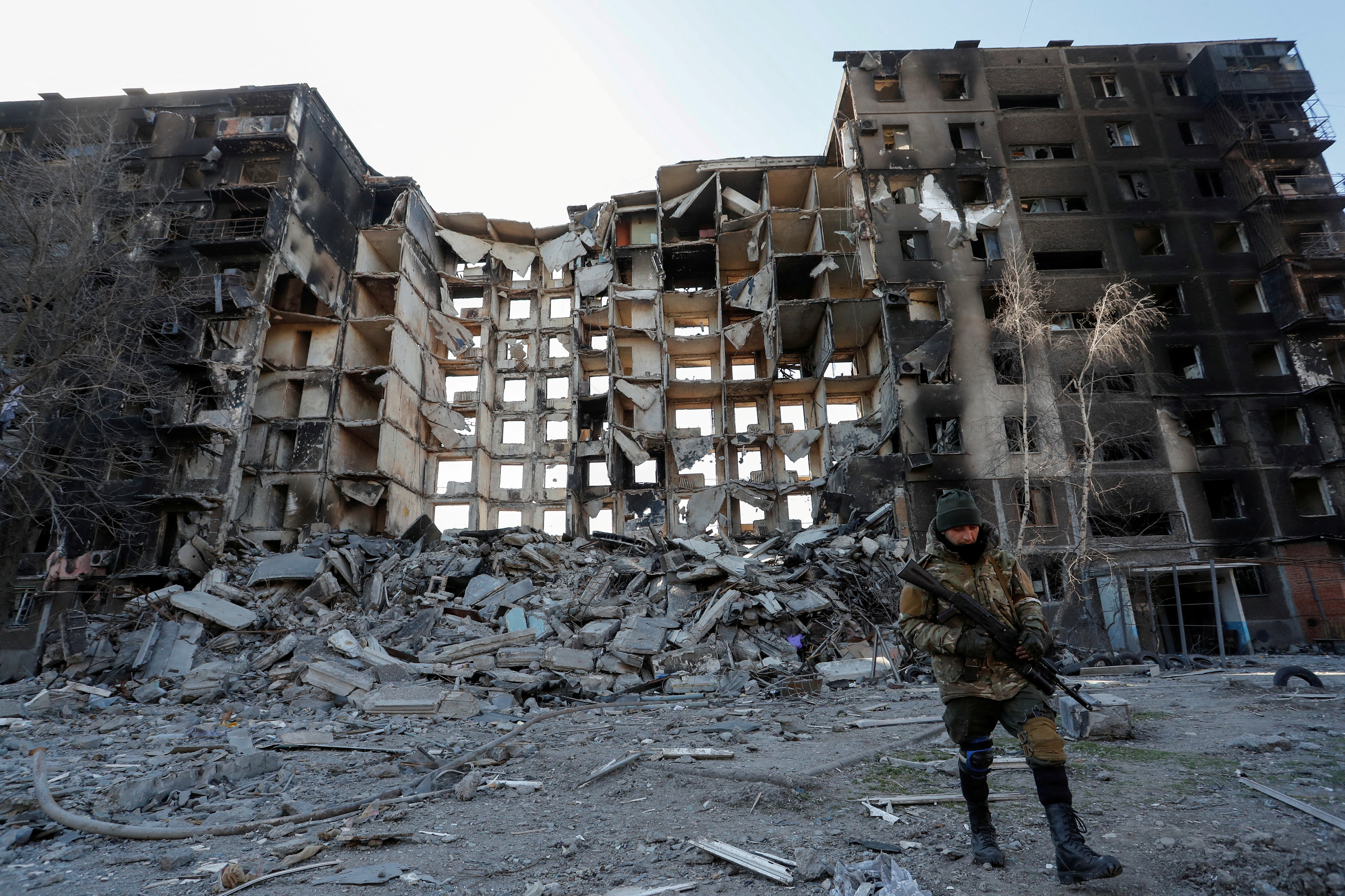 A service member of pro-Russian troops walks near an apartment building destroyed in the besieged southern port city of Mariupol on March 28, 2022.&nbsp; (Reuters Photo)
