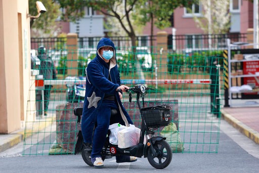 A man rides past a roadblock with his deliveries at a residential community under lockdown in Shanghai, China, (AP) A man rides past a roadblock with his deliveries at a residential community under lockdown in Shanghai, China, (AP)