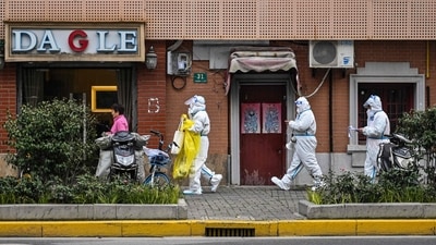 Health workers wearing protective gear as a measure against the Covid-19 coronavirus walk down a street in Jing'an district in Shanghai. (AFP)