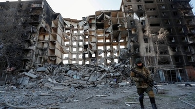 A service member of pro-Russian troops walks near an apartment building destroyed in the course of Ukraine-Russia conflict in the besieged southern port city of Mariupol, Ukraine. (REUTERS)