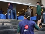 A woman wearing a Reliance JioMart vest instructs workers as they stock their products inside a Future Retail's closed Big Bazaar retail store in Mumbai.(Reuters / File)