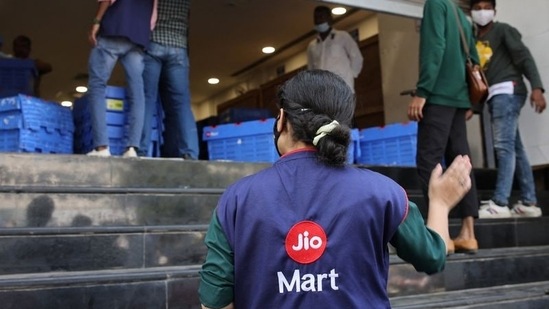 A woman wearing a Reliance JioMart vest instructs workers as they stock their products inside a Future Retail's closed Big Bazaar retail store in Mumbai.(Reuters / File)