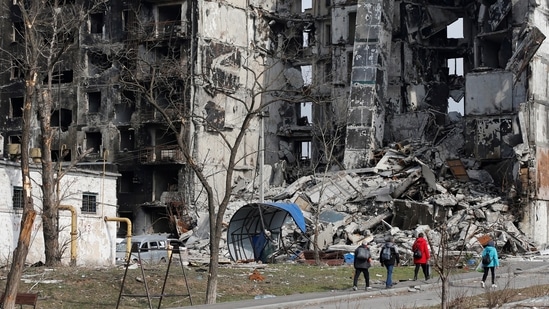 Local residents walk near an apartment building destroyed during Ukraine-Russia conflict in the besieged southern port city of Mariupol on March 30, 2022.&nbsp;(Reuters)