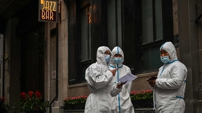 Workers, wearing protective gear, stand next to the access of a hotel on the Bund, in the Puxi area that will be in lockdown from April 1, in Shanghai (Photo by Hector RETAMAL / AFP) Workers, wearing protective gear, stand next to the access of a hotel on the Bund, in the Puxi area that will be in lockdown from April 1, in Shanghai (Photo by Hector RETAMAL / AFP)
