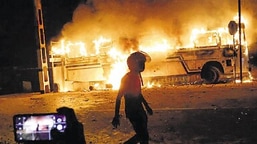 A demonstrator walks near a burning bus during a protest in Colombo on Thursday. (Reuters)