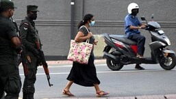 A pedestrian walks past soldiers standing on guard along a street in Colombo on April 2, 2022. &nbsp;(Photo by Ishara S. KODIKARA / AFP)
