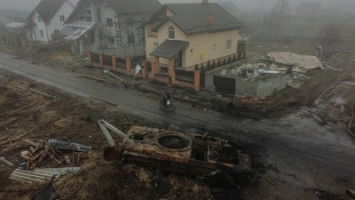 TOPSHOT - This aerial picture shows a man riding his bicycle past a burned Russian armoured vehicle, in the outskirts of Kyiv, on Friday, amid Russian invasion of Ukraine. (AFP) TOPSHOT - This aerial picture shows a man riding his bicycle past a burned Russian armoured vehicle, in the outskirts of Kyiv, on Friday, amid Russian invasion of Ukraine. (AFP)