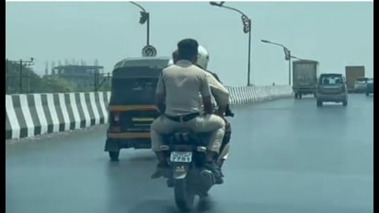 The grab from a 40-second video that went viral in which police personnel were riding triples on a two-wheeler, thus violating traffic rules, on the Mumbai-Pune Highway. The Navi Mumbai traffic police have levied a fine on the rider. (HT PHOTO)