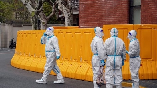 Workers in protective suits stand next to a sealed-off area before the second stage of a two-stage lockdown to curb the spread of COVID-19, in Shanghai, on March 31, 2022.&nbsp;(Reuters photo)