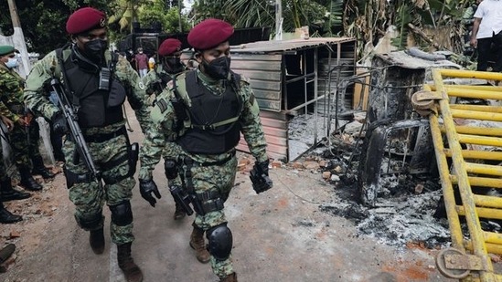 Sri Lankan army commandos walk past the damaged vehicles after they were set on fire by demonstrators at the top of the road to Sri Lankan President Gotabaya Rajapaksa's residence during a protest against him.&nbsp;(REUTERS)