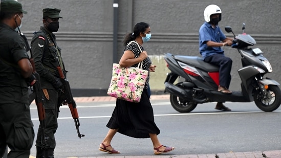 A pedestrian walks past soldiers standing on guard along a street in Colombo on April 2, 2022. &nbsp;(Photo by Ishara S. KODIKARA / AFP)(AFP)