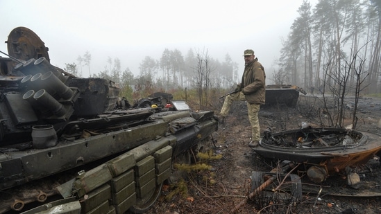 A Ukrainian service member stands amid destroyed Russian military vehicles, as Russia's attack on Ukraine continues, in the village of Dmytrivka in Kyiv region,&nbsp;