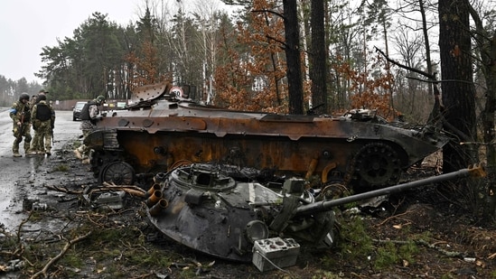 Ukrainian soldiers stand by the wreckage of a Russian armoured vehicle in Dmytrivka village, west of Kyiv on Saturday.(AFP)