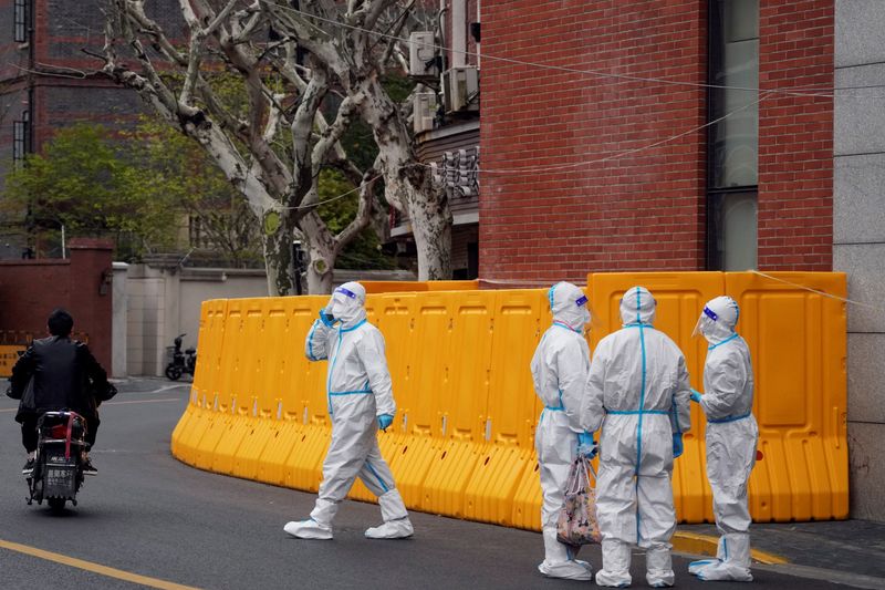 Workers in protective suits stand next to a sealed-off area before the second stage of a two-stage lockdown to curb the spread of COVID-19, in Shanghai, on March 31, 2022.&nbsp; (Reuters photo)