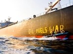 Activists of the environmental organisation Greenpeace paint the words 'Oil fuels war' on the hull of a ship carrying Russian oil near the German island Fehmarn, Germany. (Frank Molter/dpa via AP)