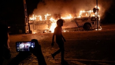 A person takes a photo as a demonstrator walks near a bus that was set on fire at the top of the road to Sri Lankan President Gotabaya Rajapaksa's residence during a protest against him. (File image) (REUTERS/Dinuka Liyanawatte)