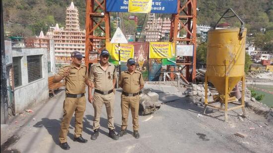 Local policemen guarding the Laxman Jhula gate after one of its wires snapped on Sunday. (HT PHOTO.)