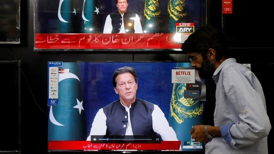 A shopkeeper tunes a TV screen to watch the speech of Pakistani Prime Minister Imran Khan in Islamabad.