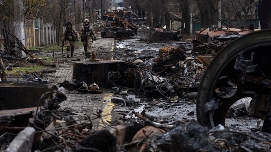 Soldiers walk amid destroyed Russian tanks in Bucha, in the outskirts of Kyiv, Ukraine. Ukrainian troops are finding brutalized bodies and widespread destruction in the suburbs of Kyiv, sparking new calls for a war crimes investigation and sanctions against Russia.(AP)