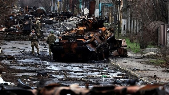 A soldier takes a photograph of his comrade as he poses beside a destroyed Russian tank and armoured vehicles, amid Russia's invasion on Ukraine in Bucha, in Kyiv region(Reuters)