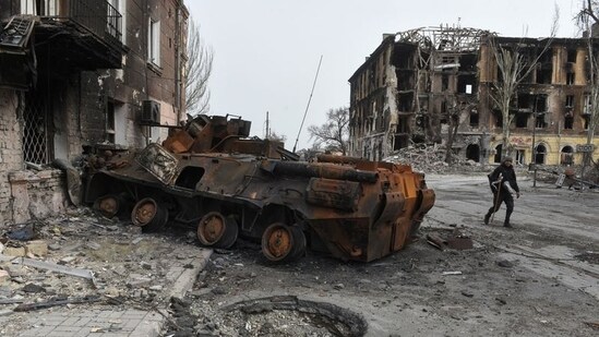 A man walks past a burnt armoured personnel carrier near buildings destroyed in the course of Ukraine-Russia conflict in the southern port city of Mariupol, Ukraine. (REUTERS/Stringer)