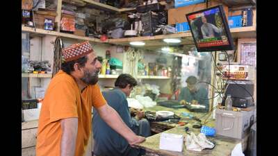 A shopkeeper watches on television Pakistan's Prime Minister Imran Khan while he takes telephone calls from the public, Islamabad, April 4, 2022 (AFP)