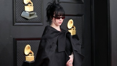 Billie Eilish attended the 64th Grammy Awards in a funky and sculptural ensemble by Rick Owens. She wore a coat wrapped around a dress with rubber-soled boots and skinny sunglasses and finished it off with one of her signature sharp updos. (REUTERS)