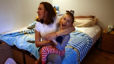 Ukrainian refugee Alexandra Zhuravel, 38, holds her daughter Alevtina Bravorichenko-Crane, 8, in their bedroom at the Benedictine Sisters Monastery, which has welcomed refugees amid Russia's invasion of Ukraine, in Jaroslaw, Poland. (REUTERS)